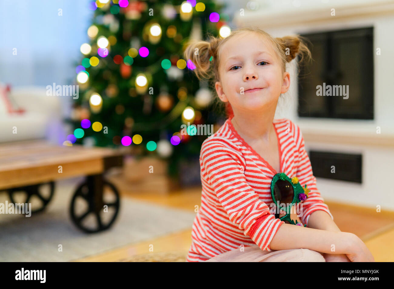 Adorable kleine Mädchen zu Hause schön für Weihnachten mit Kamin, Baum, Strümpfe und Lichtern geschmückt Stockfoto