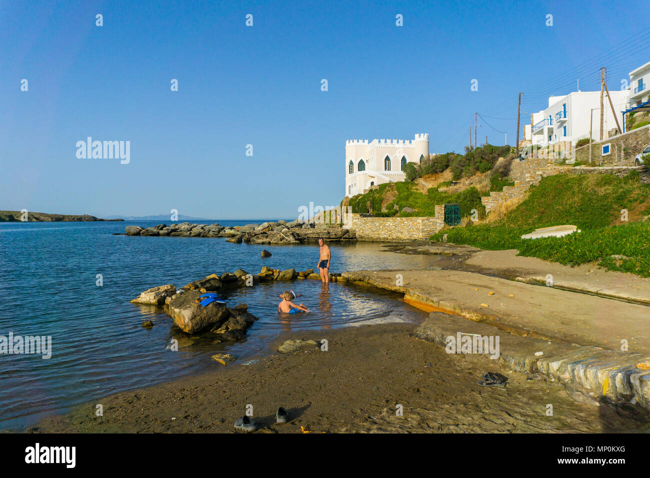 Die Menschen baden im heissen Quellwasser in den Strand von Loutra (Bäder) in Kythnos. Heiße Mineralquelle Wasser fließt durch einen Kanal und vermischt sich mit dem Meer Stockfoto