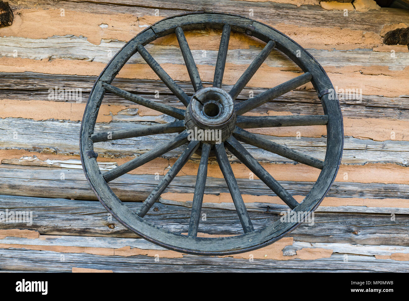 Alte verwitterte Wagenrad auf Log Cabin Wand Stockfoto
