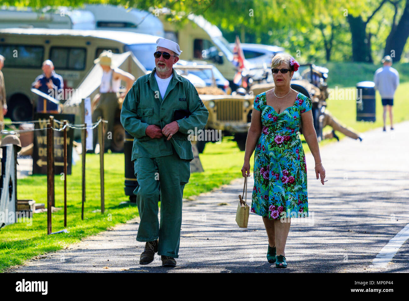 Gruß an die 40s, beliebte Veranstaltung in England. Reenactor Paar mittleren Alters, die er im Zweiten Weltkrieg grüne US Navy Uniform, die sie in Dress, entlang Weg. Stockfoto