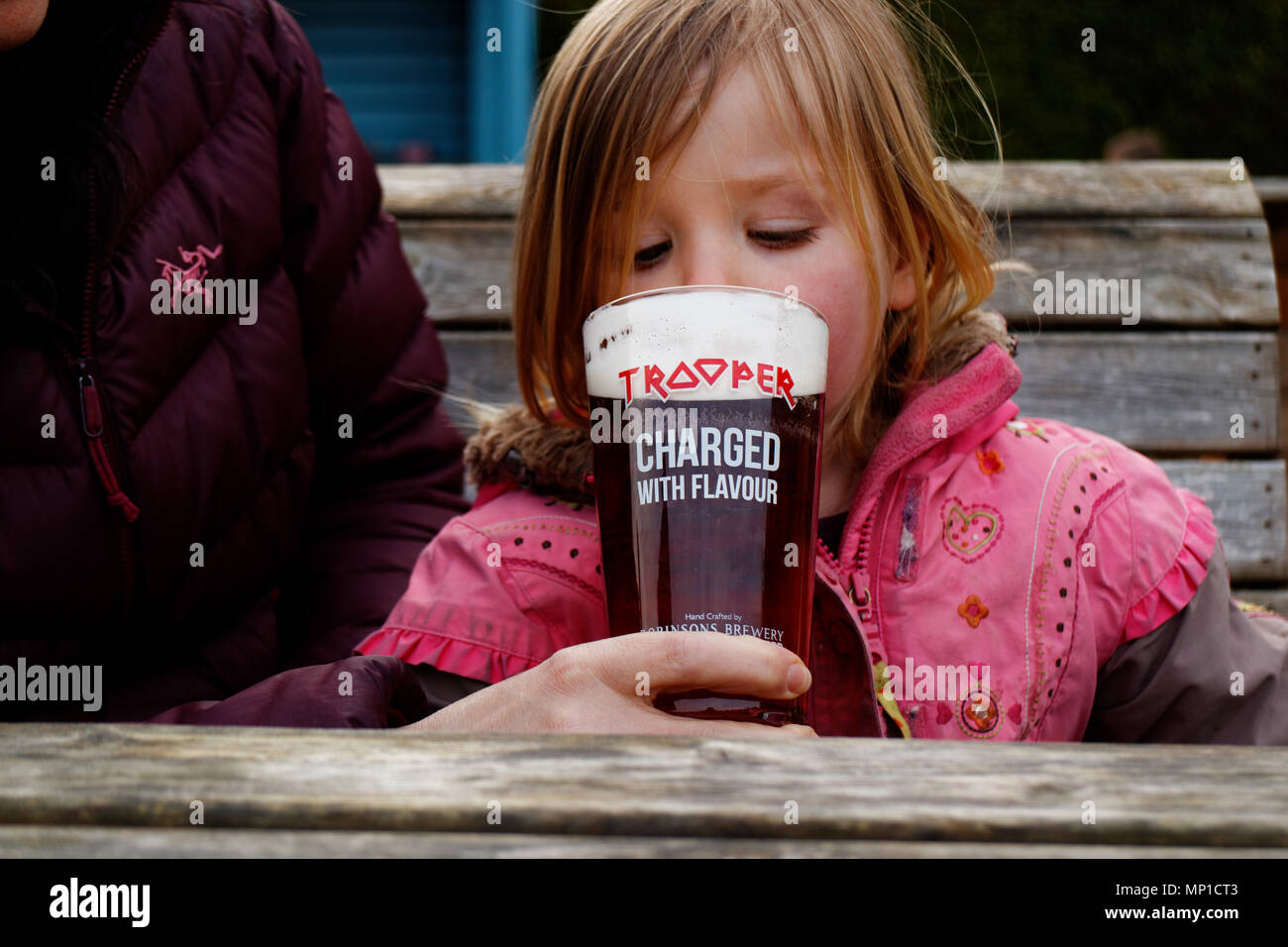 Ein kleines Mädchen (3 Jahre alt) Tasting von einem Pint Trooper Bier, in Zusammenarbeit mit der Britischen Heavy Metal Gruppe Iron Maiden gemacht Stockfoto