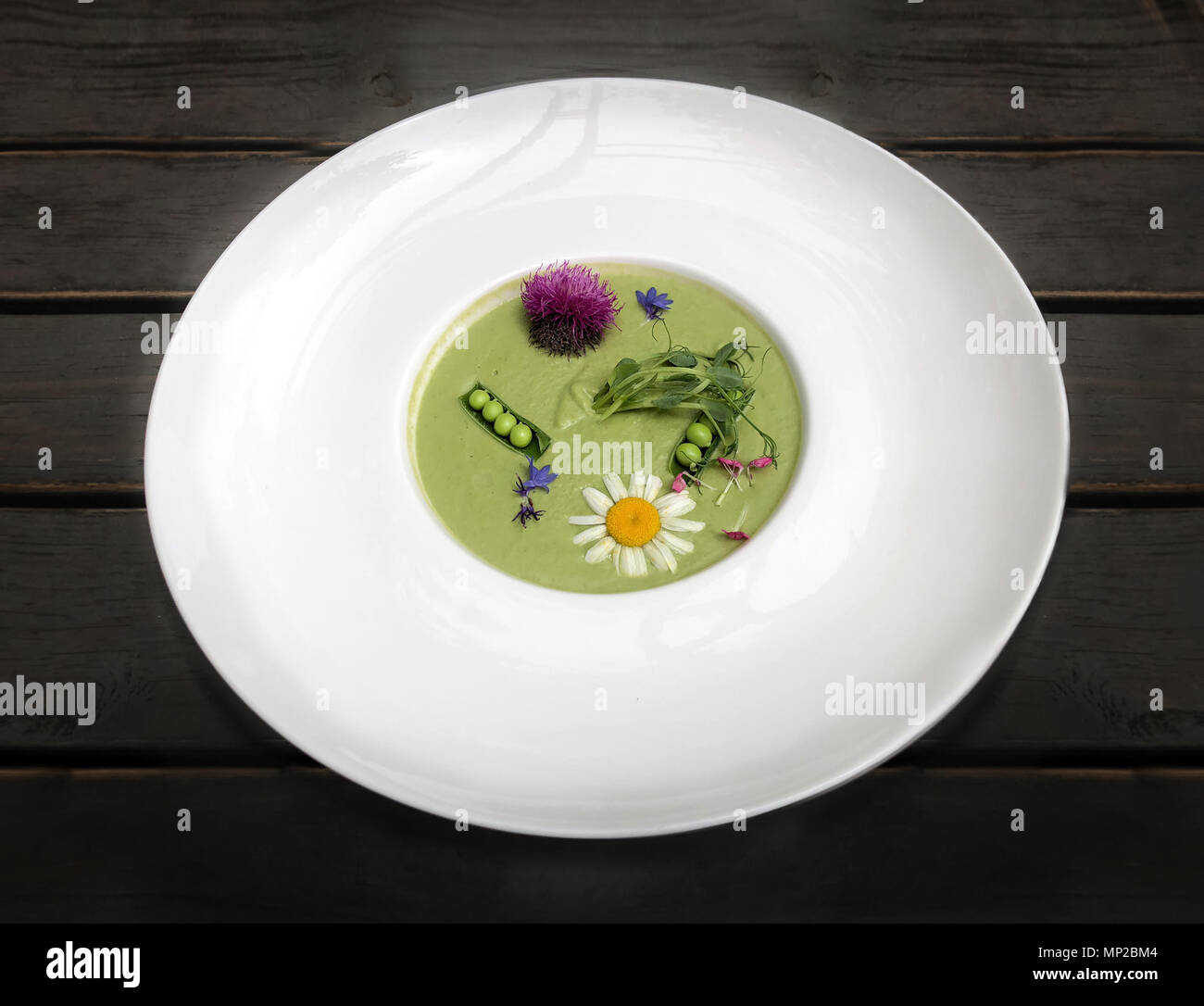 Gemüsesuppe Kartoffelpüree grüne Erbsen und Brokkoli, mit Blumen und duftende Kräuter eingerichtet. Das Gericht genossen. Stockfoto