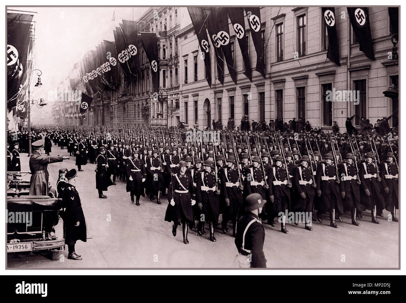 Adolf Hitler in seiner oben offenen Mercedes Auto begrüßt eine Parade von seiner Leibgarde Regiment, der 1. SS-Division Leibstandarte Waffen-SS mit Gebäuden geschmückt mit Hakenkreuzfahnen Januar 30th, 1937 Stockfoto