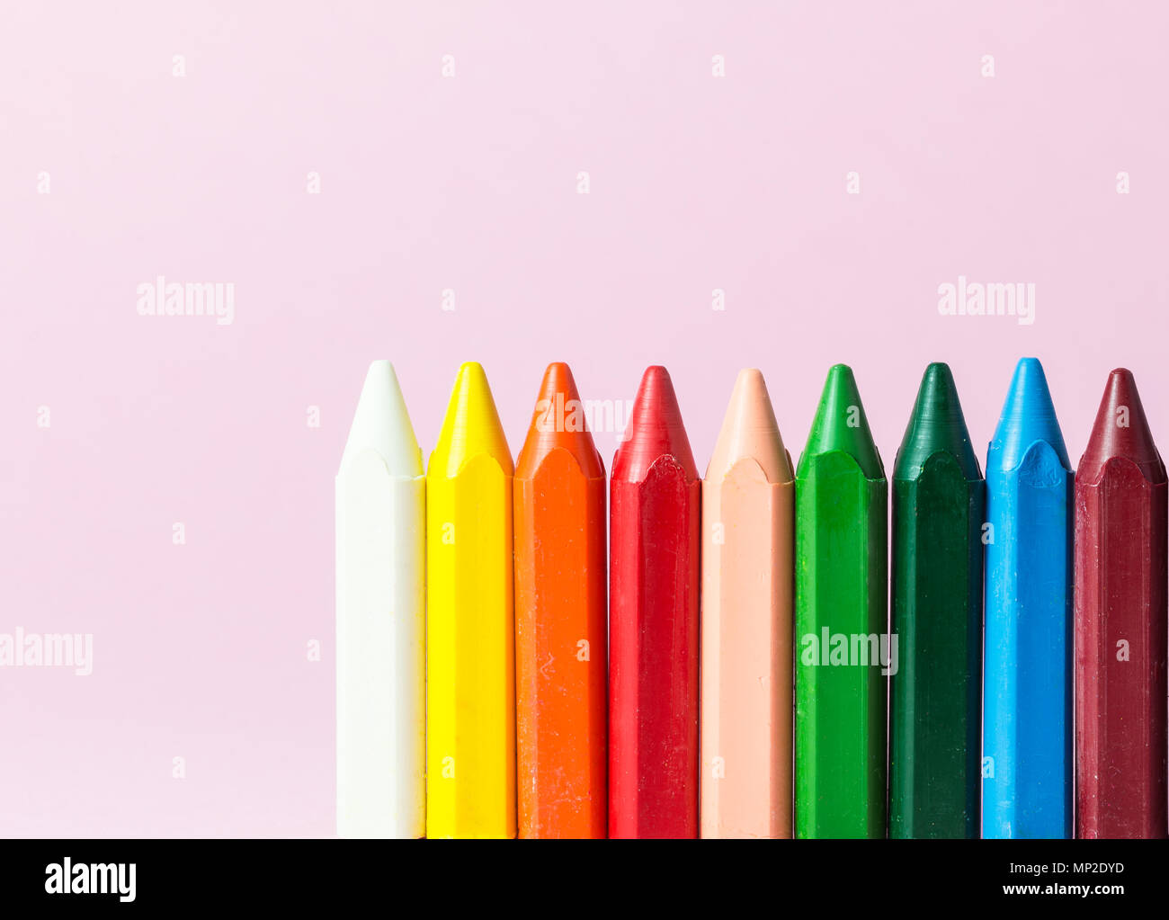 Neue Wachsmalstifte in verschiedenen Farben auf einem rosa Hintergrund isoliert Stockfoto