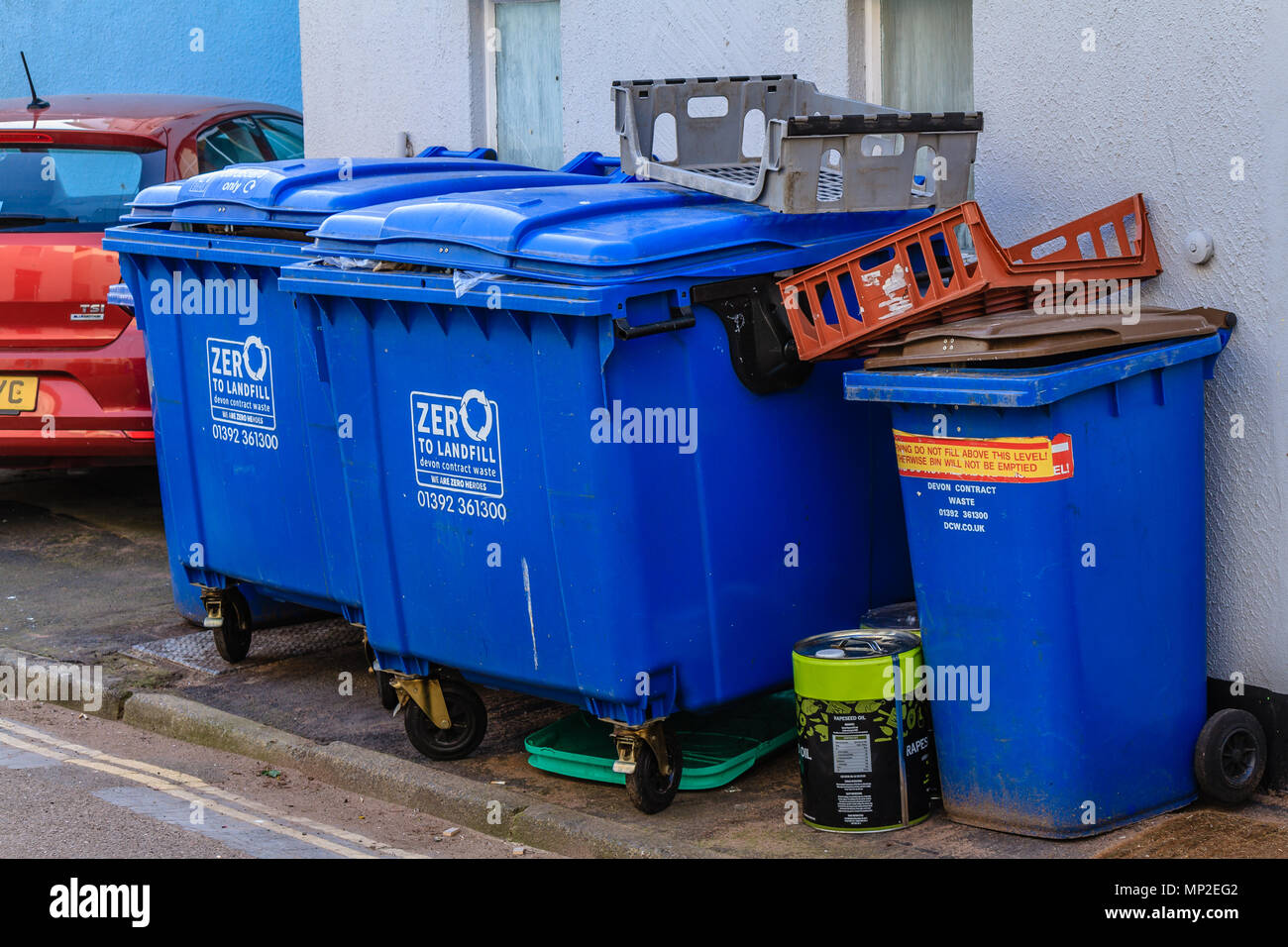 Reihe der großen blauen kommerzielle Verwertung der Behälter in einer Nebenstraße hinter einem gewerblichen Räumen. Teignmouth, Devon. Feb 2018. Stockfoto