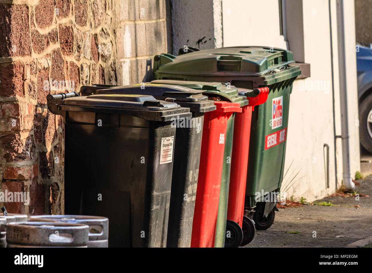 Reihe der großen bunten Mülleimern in einer Seitenstraße. Teignmouth, Devon. Feb 2018. Stockfoto