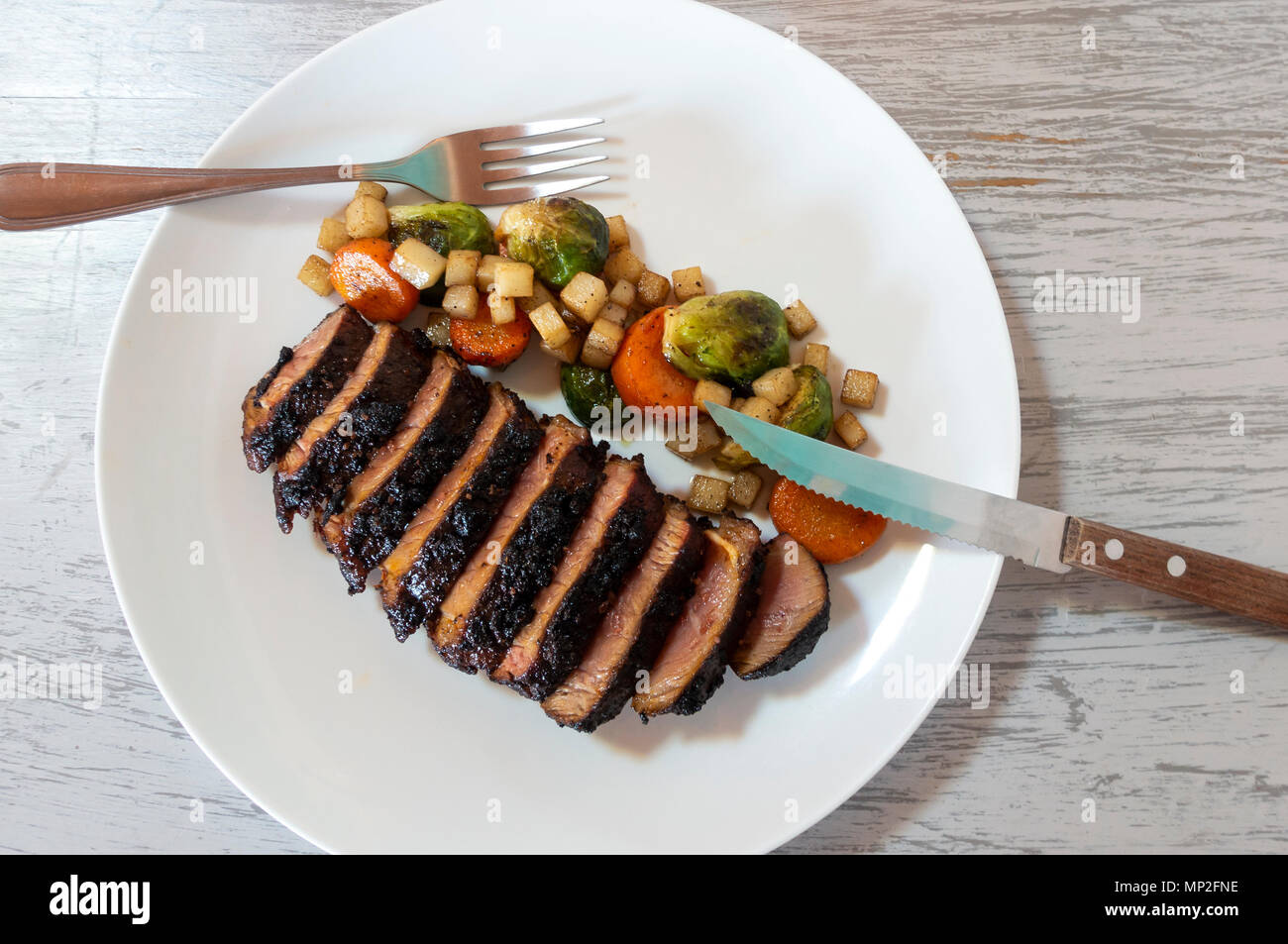 In Scheiben geschnittene Steak mit gegrilltem Gemüse - - Karotten, Kartoffeln und Rosenkohl Stockfoto