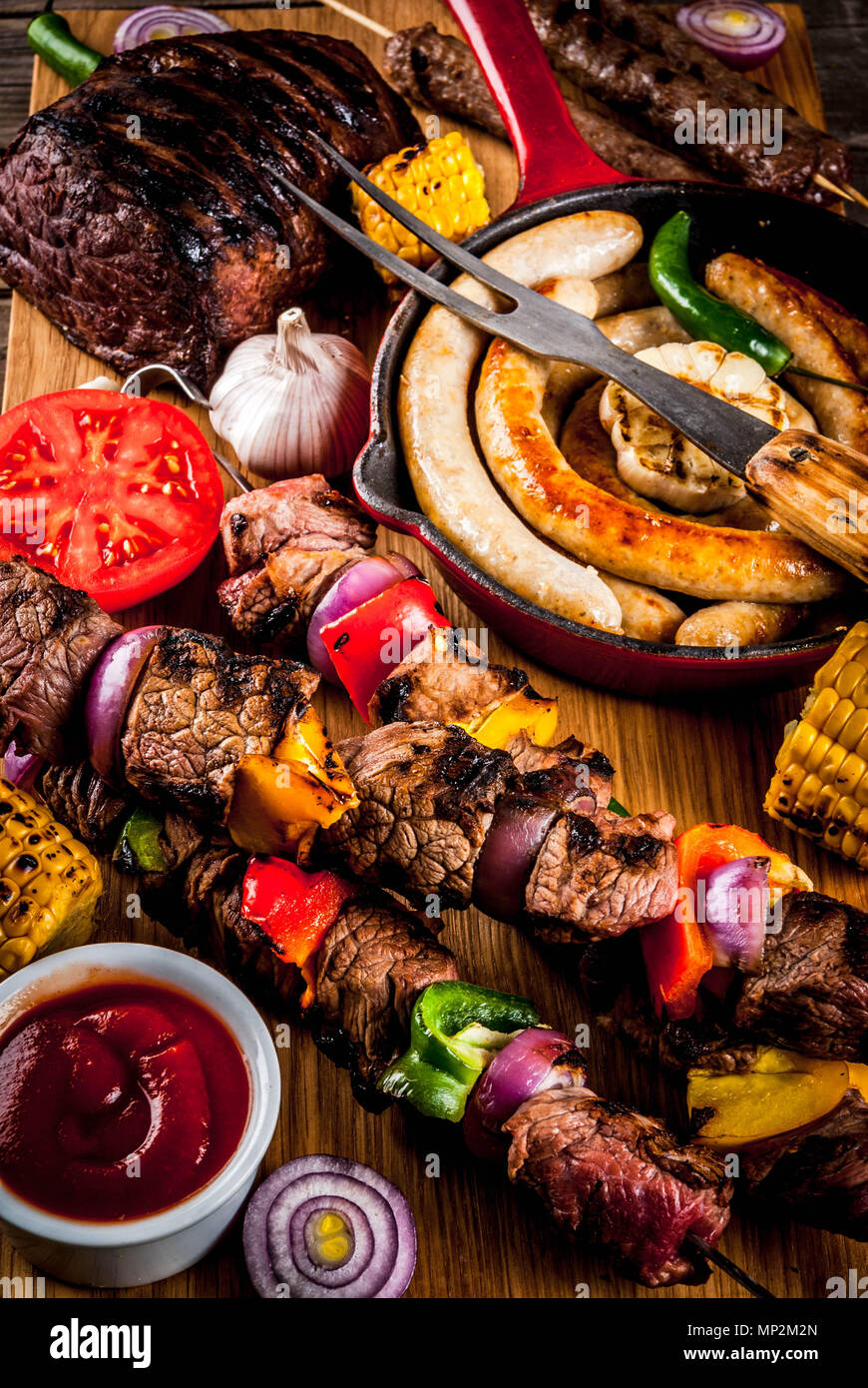 Sortiment verschiedene Barbecue Grill Fleisch, bbq Party fest - Shish Kebab, Würstchen, gegrillten Fleisch Filet, frisches Gemüse, Soßen, Gewürze, auf alten Woo Stockfoto