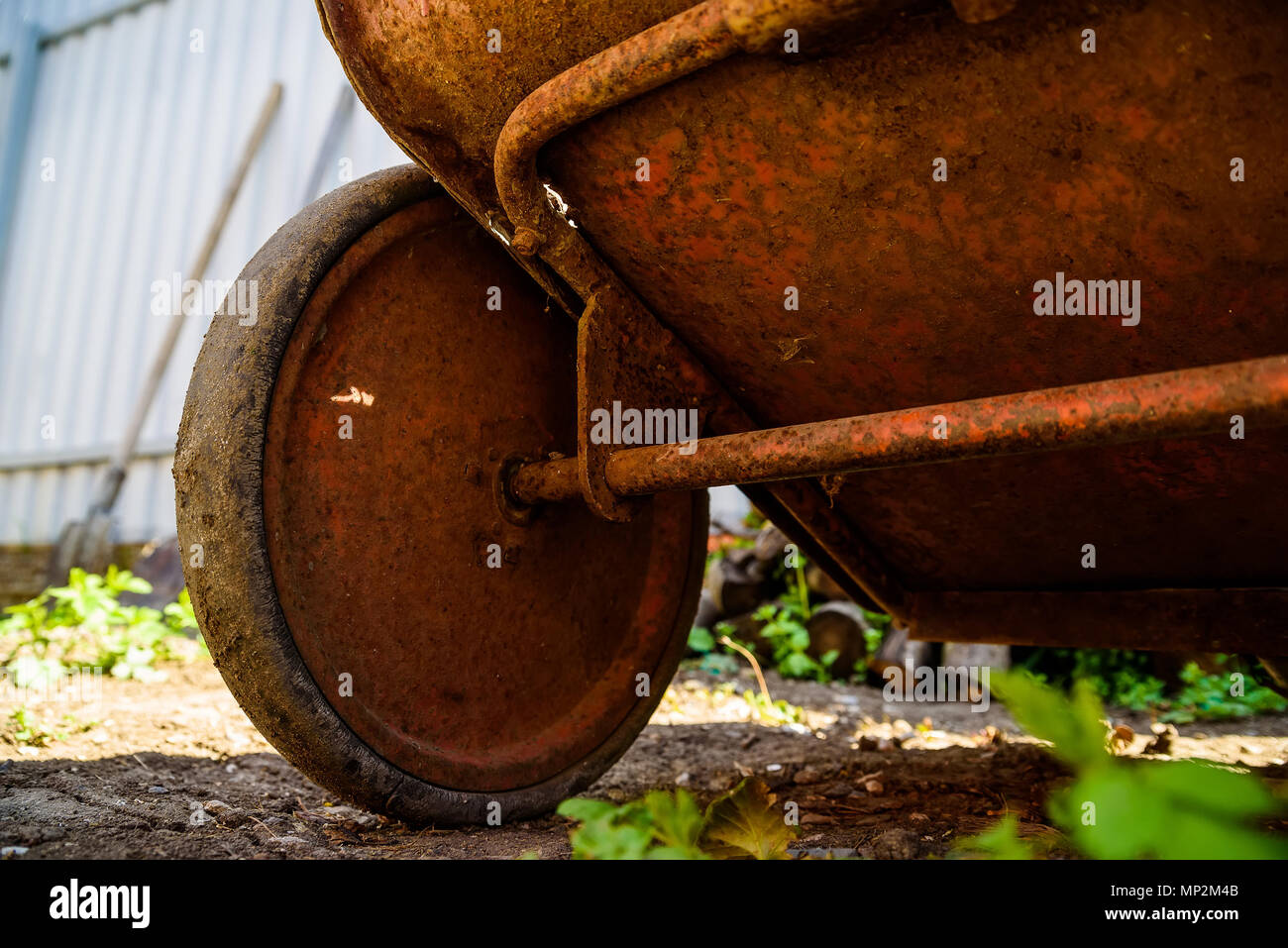 In der Nähe von Teilen der veralteten Schubkarre in Rust im Garten gehalten abgedeckt Stockfoto In der Nähe von Teilen der veralteten Schubkarre in Rust im Garten gehalten abgedeckt Stockfoto