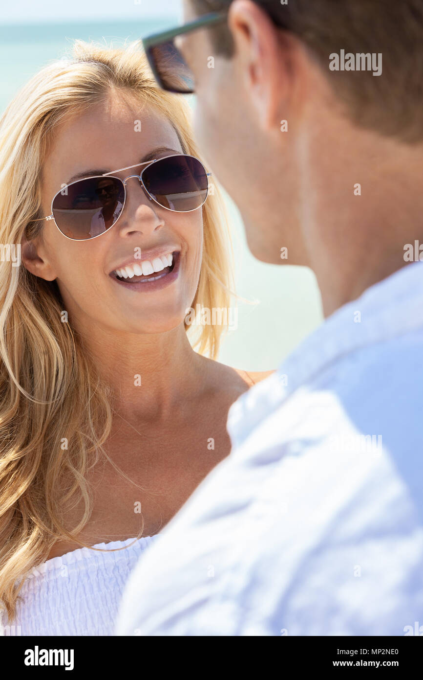 Porträt eines Mannes und einer Frau romantisches Paar mit perfekte Zähne tragen weiße Kleidung und Sonnenbrille am Strand Stockfoto