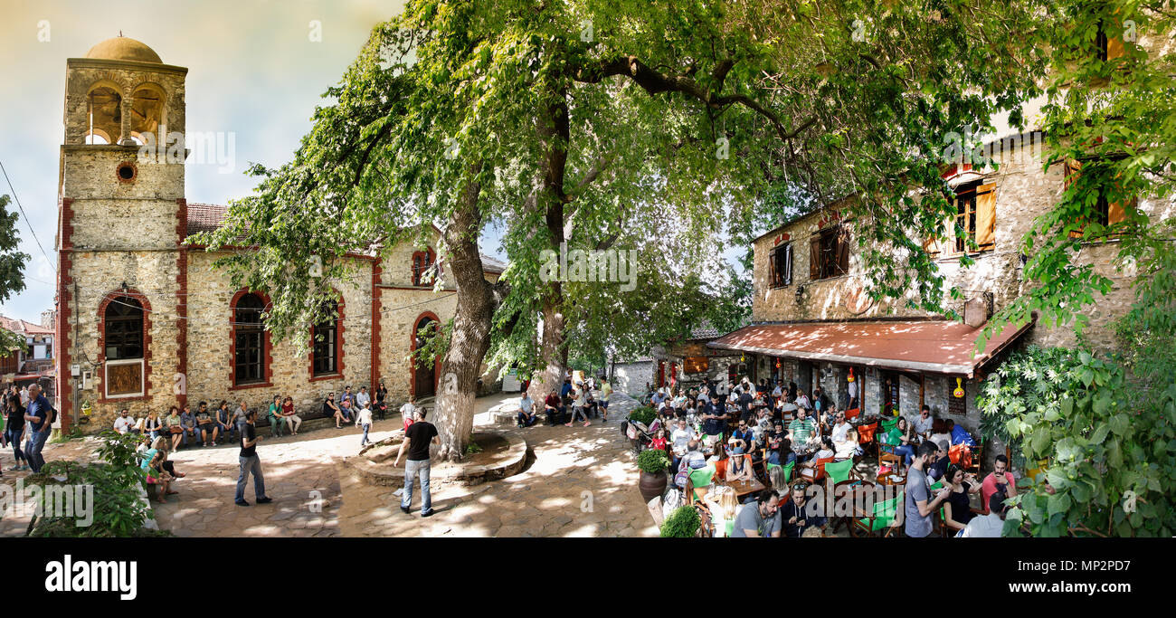 Palios Panteleimonas, Griechenland - Mai 1th, 2018: Panorama des zentralen Platzes, der ombu Tree und der Orthodoxen Kirche St. Panteleimon, wo Menschen enj Stockfoto
