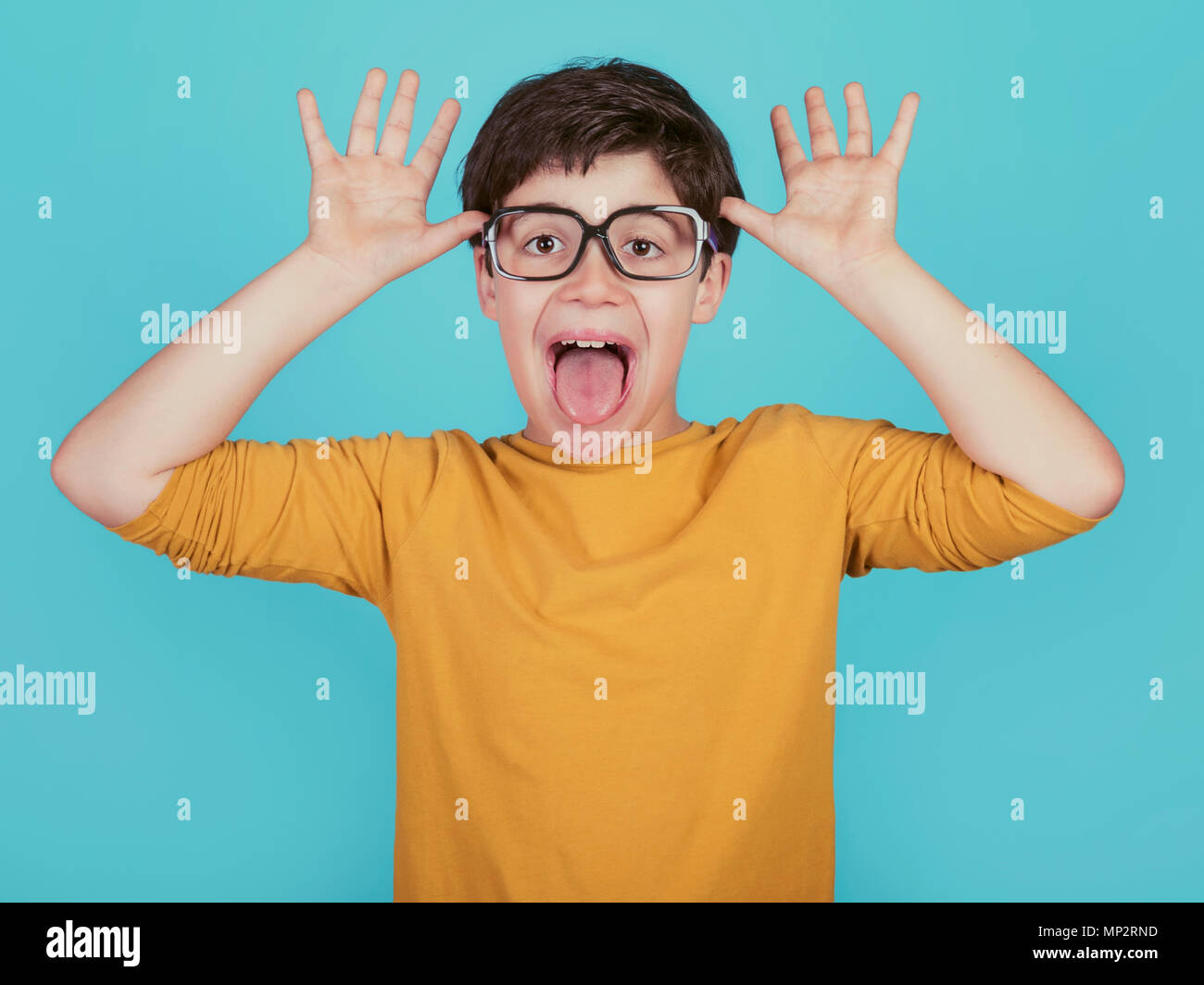 Lustig Junge mit Brille zeigen, seine Zunge auf blauem Hintergrund Stockfoto