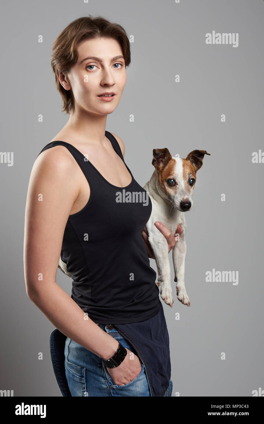 Junge Frau, Hund unter dem Arm auf dem grauen studio Hintergrund Stockfoto