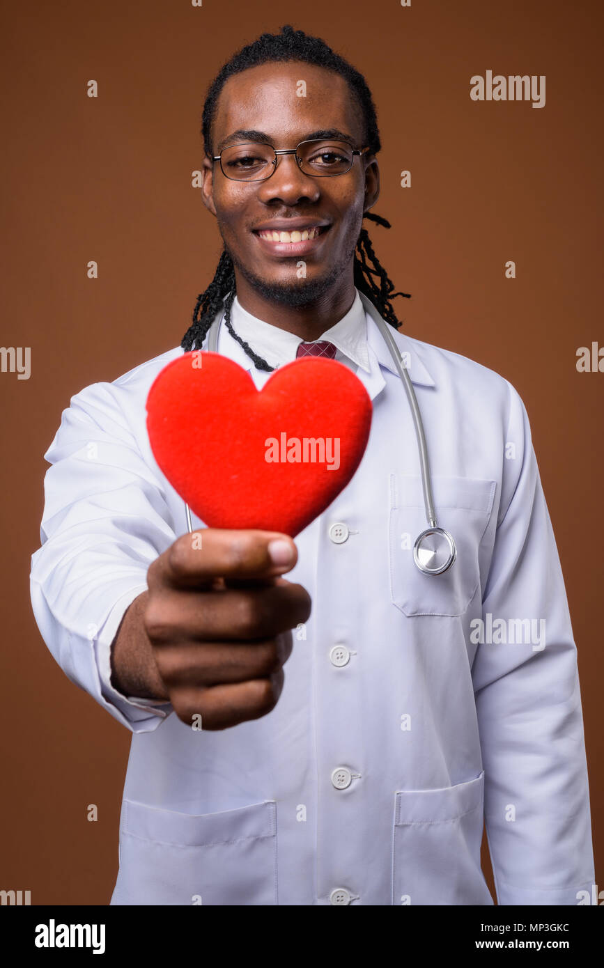 Junge schöne afrikanischer Mann Arzt gegen braunen Hintergrund Stockfoto