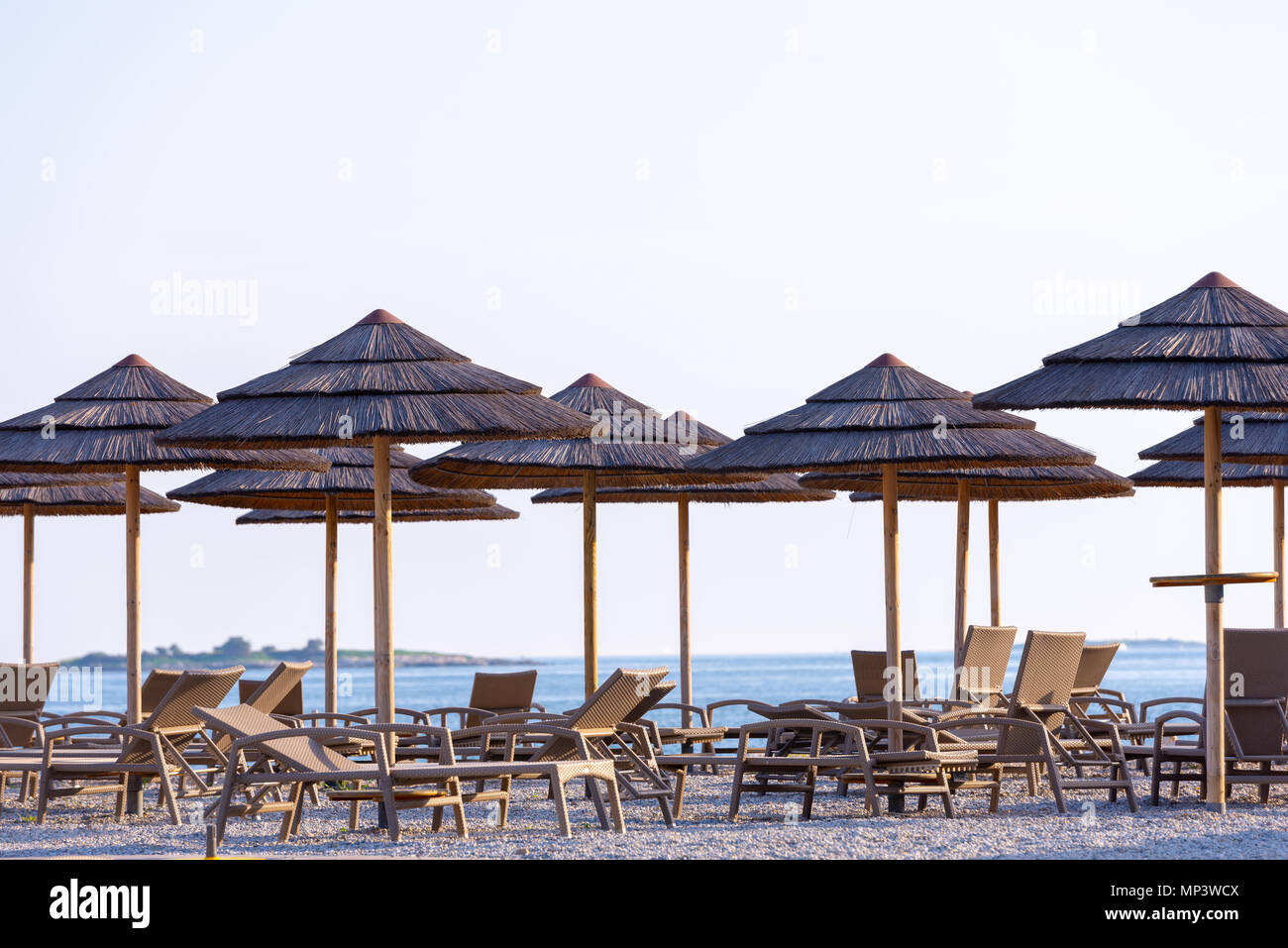 Reed Sonnenschirme und Liegestühle am Strand Stockfoto