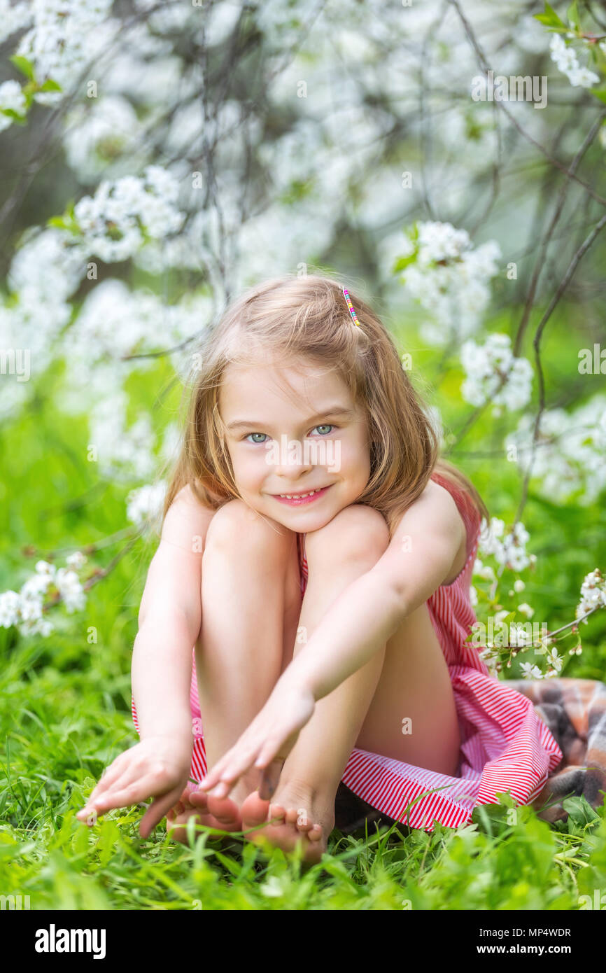 Glückliche kleine Mädchen in Kirschblüte Garten Stockfoto