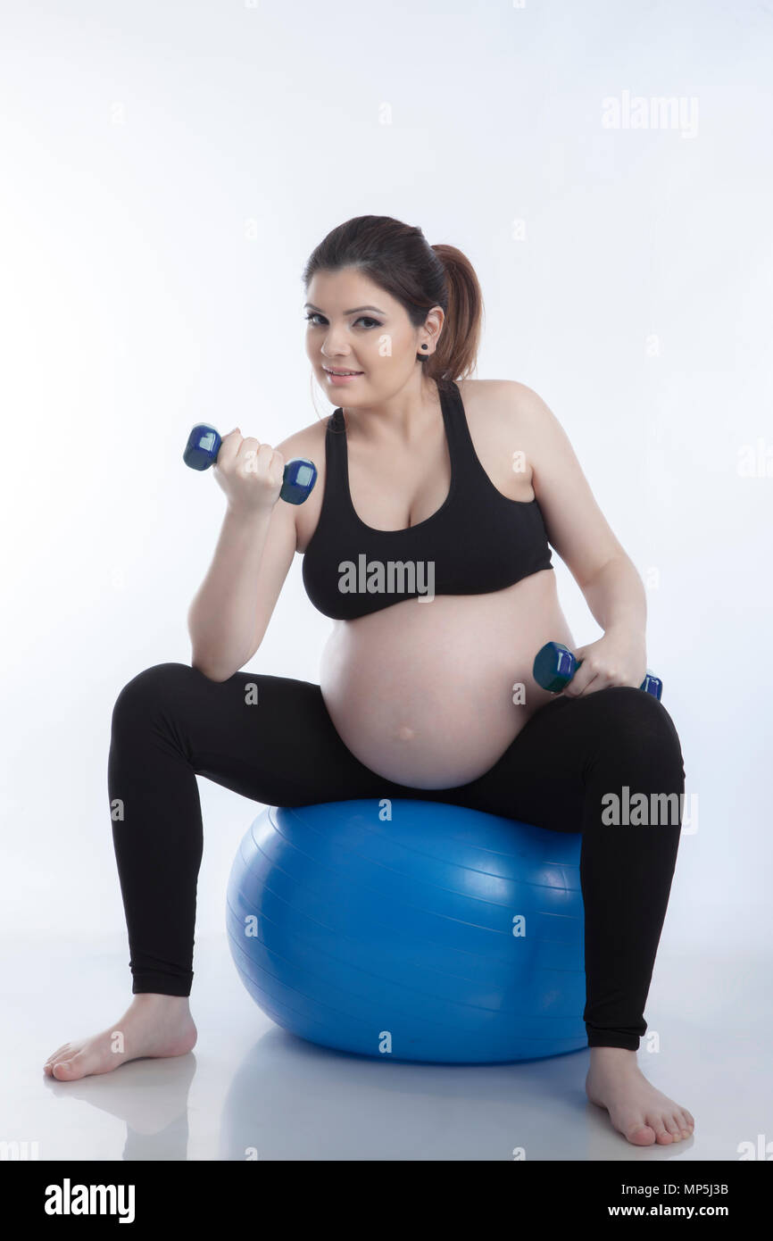 Schwangere Frau ist Übungen mit Gymnastikball auf weißem Hintergrund Stockfoto