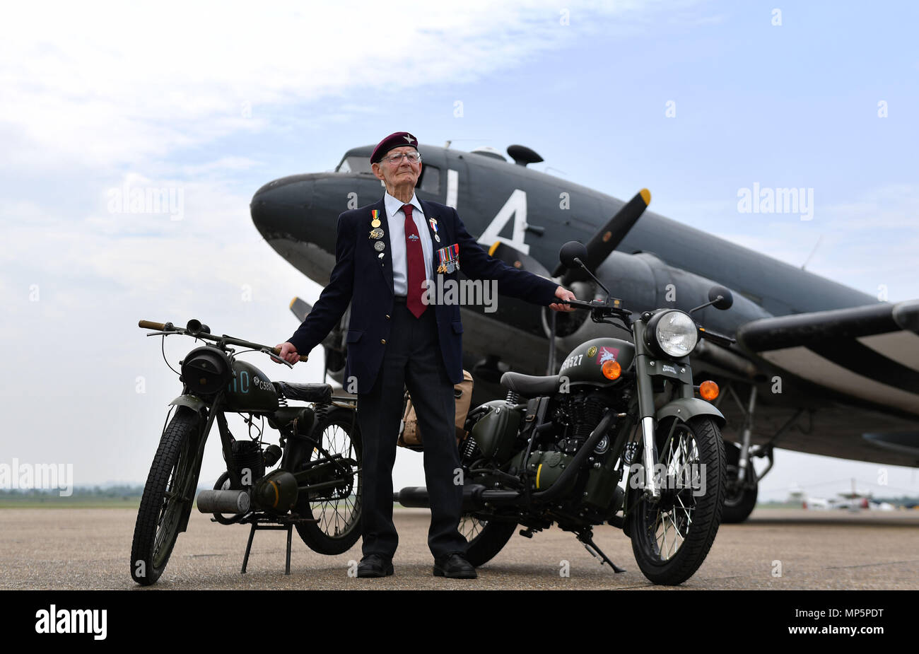 Fred Glover, 92, der in den Parachute Regiment während des Zweiten Weltkrieges diente, steht auf der Landebahn im Imperial War Museum Duxford mit einer limited edition Royal Enfield "Classic 500cc Pegasus' Motorrad (rechts) Inspiriert durch das Erbe des Royal Enfield WD/RE 125 cc bekannt als die 'Flying Flea" (links). Stockfoto