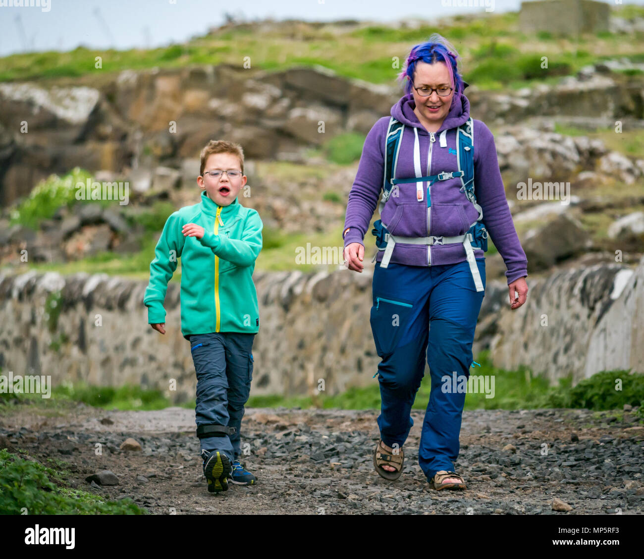 Frau mit gefärbten Haaren und Junge mit Brille und Bein Klammer zu Fuß auf die Insel kann, Schottland, Großbritannien Stockfoto