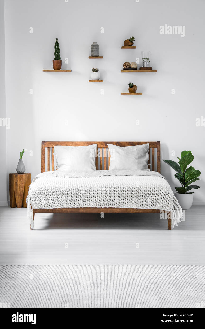 Holz- Doppelbett mit zwei Kissen und eine Decke, und kleine Regale über in  ein weißes Schlafzimmer Innenraum eingerahmt. Real Photo Stockfotografie -  Alamy