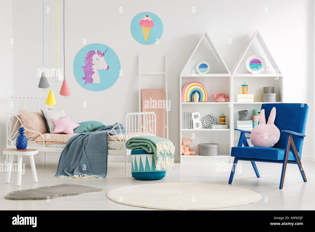 Süße Schlafzimmer für ein Kind mit einem blauen Sessel, Kaninchen Kissen, Bett, Einhorn, Eis Poster und Regale Stockfoto