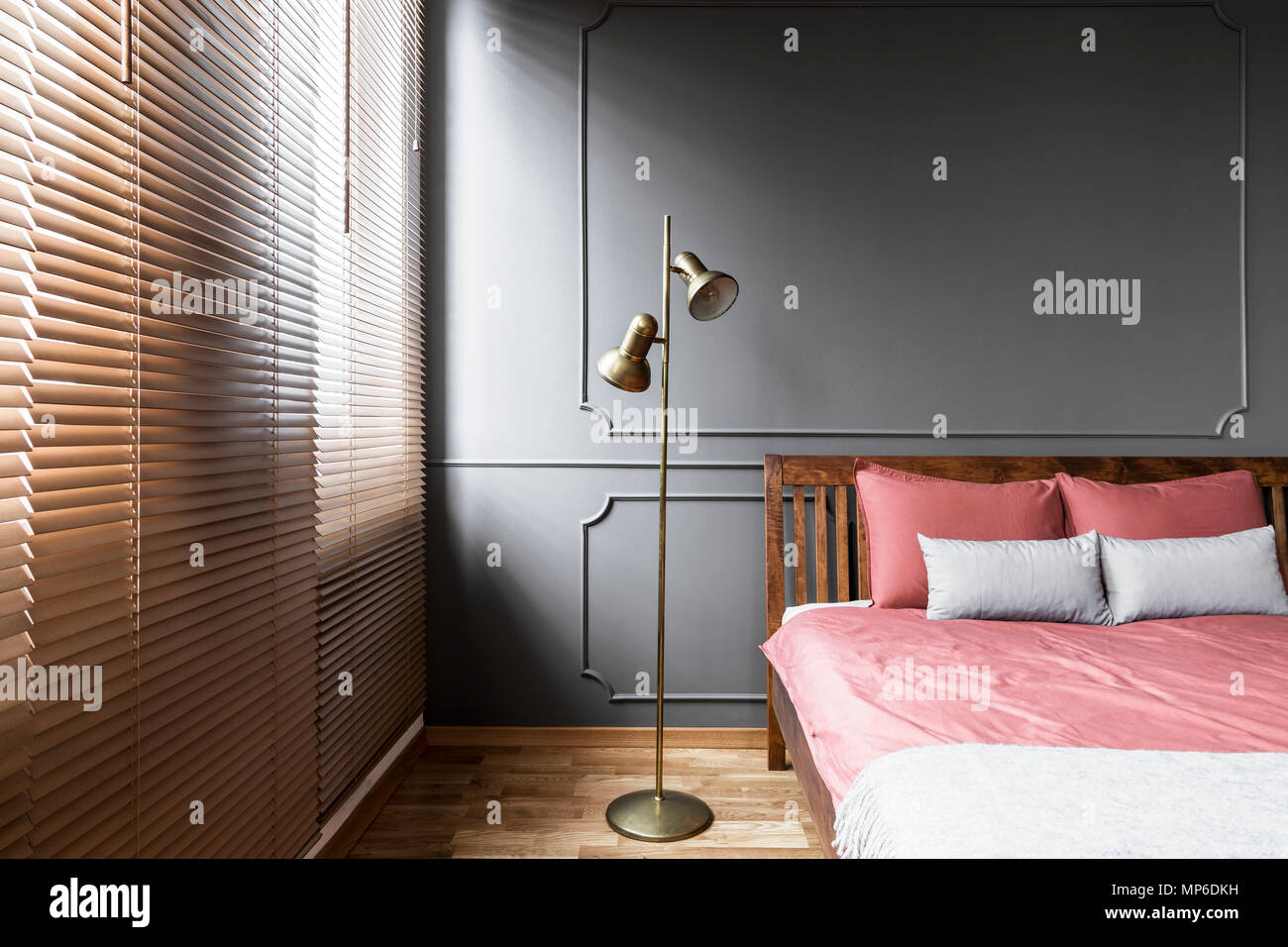 Jalousien und golden Lampe in dunklen und eleganten Schlafzimmer Innenraum  mit rosa Blätter auf einem Bett aus Holz und Kante an der Wand. Real Photo  Stockfotografie - Alamy