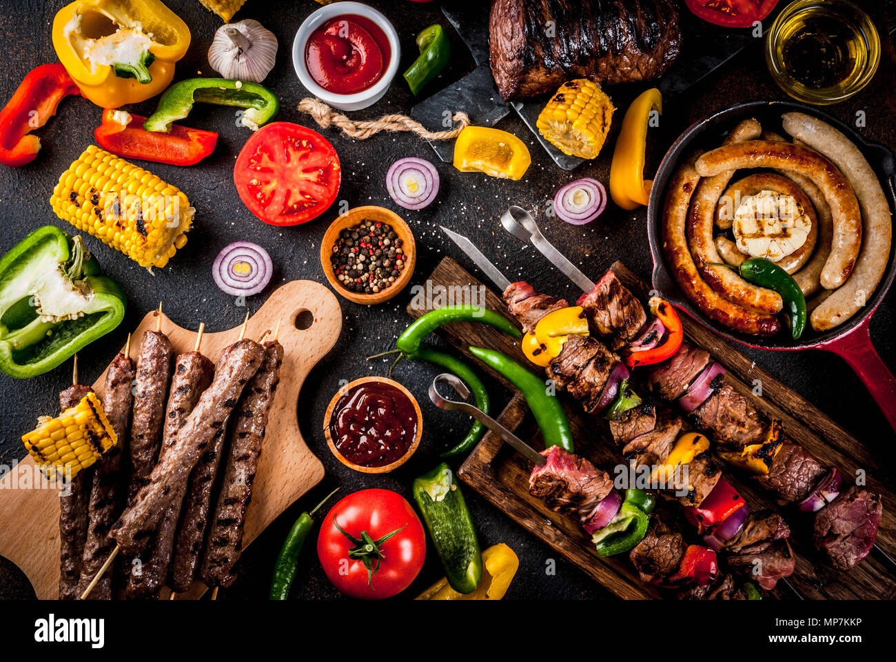 Sortiment verschiedene Barbecue Grill Fleisch, bbq Party fest - Shish Kebab, Würstchen, gegrillten Fleisch Filet, frisches Gemüse, Soßen, Gewürze, dunklen Rusty Stockfoto