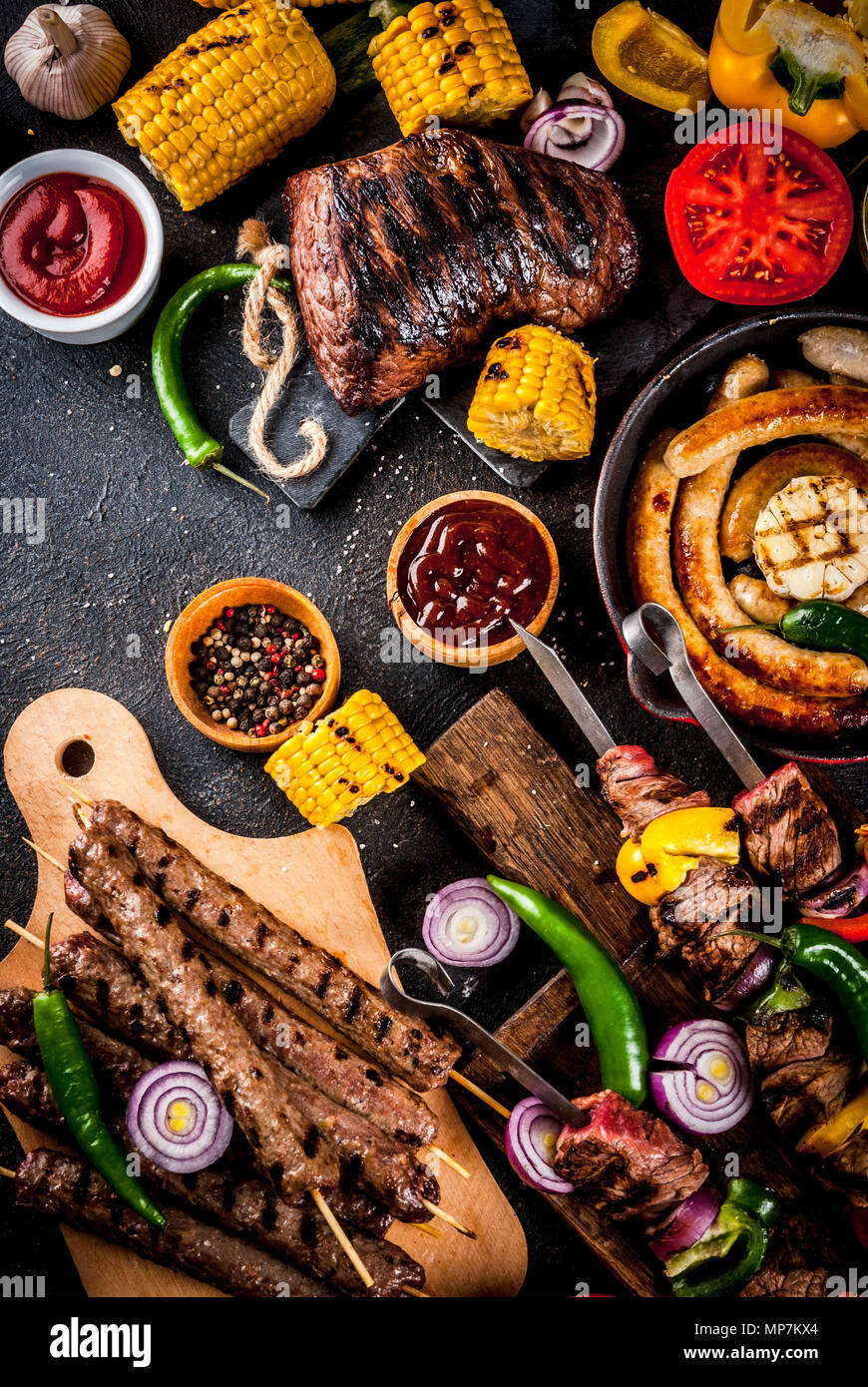 Sortiment verschiedene Barbecue Grill Fleisch, bbq Party fest - Shish Kebab, Würstchen, gegrillten Fleisch Filet, frisches Gemüse, Soßen, Gewürze, dunklen Rusty Stockfoto