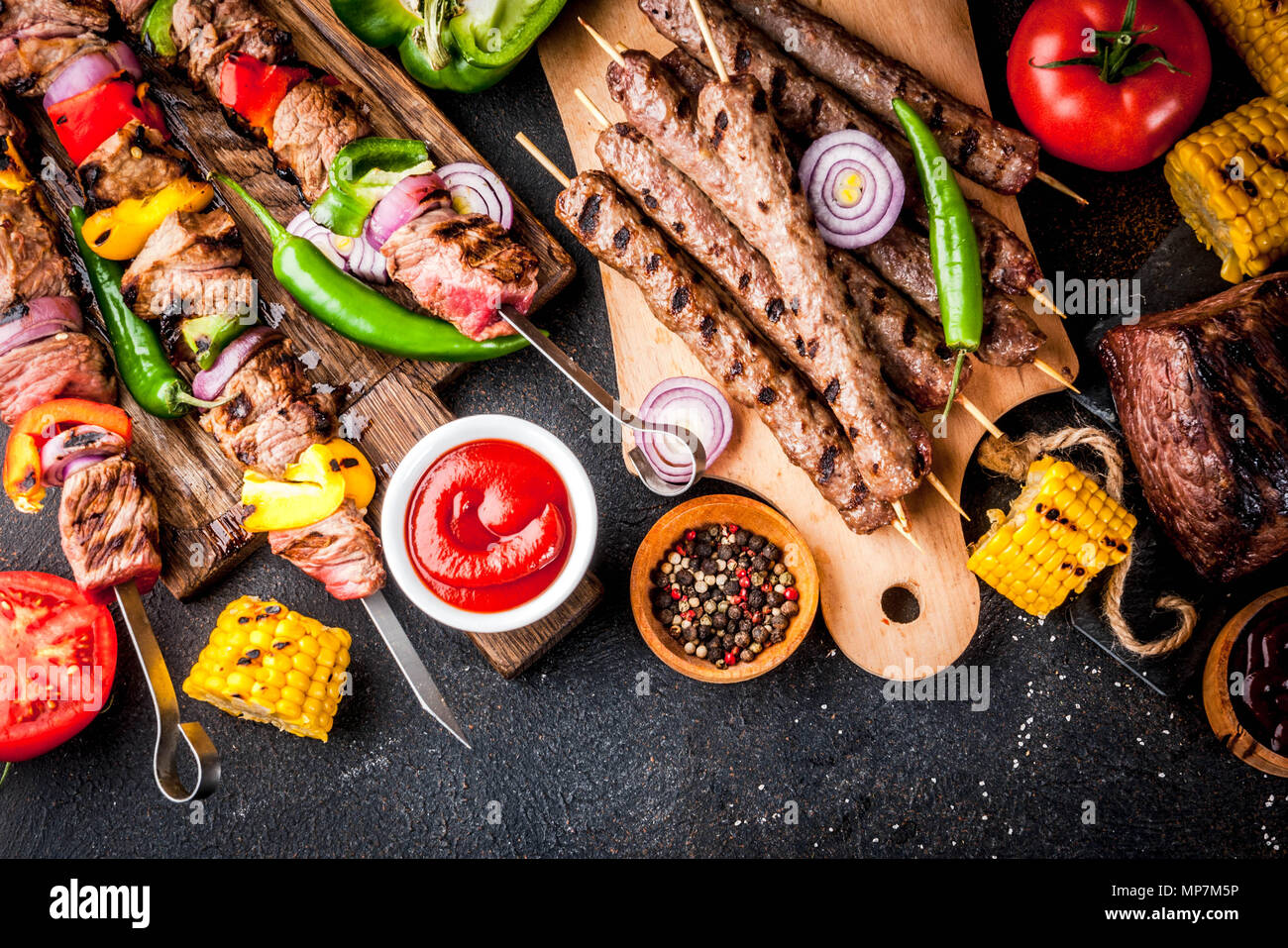 Sortiment verschiedene Barbecue Grill Fleisch, bbq Party fest - Shish Kebab, Würstchen, gegrillten Fleisch Filet, frisches Gemüse, Soßen, Gewürze, dunklen Rusty Stockfoto