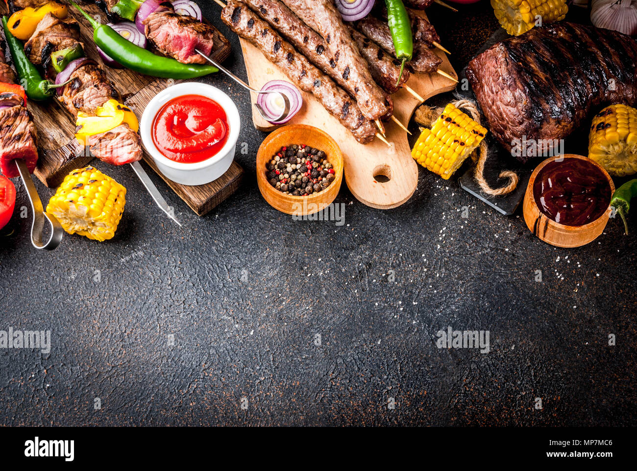 Sortiment verschiedene Barbecue Grill Fleisch, bbq Party fest - Shish Kebab, Würstchen, gegrillten Fleisch Filet, frisches Gemüse, Soßen, Gewürze, dunklen Rusty Stockfoto