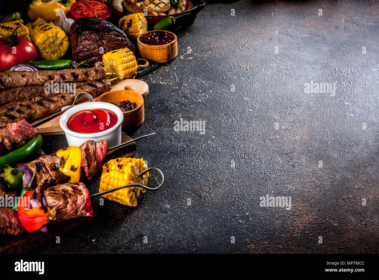Sortiment verschiedene Barbecue Grill Fleisch, bbq Party fest - Shish Kebab, Würstchen, gegrillten Fleisch Filet, frisches Gemüse, Soßen, Gewürze, dunklen Rusty Stockfoto