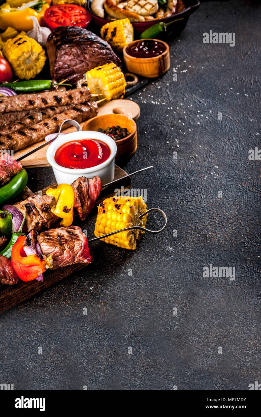 Sortiment verschiedene Barbecue Grill Fleisch, bbq Party fest - Shish Kebab, Würstchen, gegrillten Fleisch Filet, frisches Gemüse, Soßen, Gewürze, dunklen Rusty Stockfoto