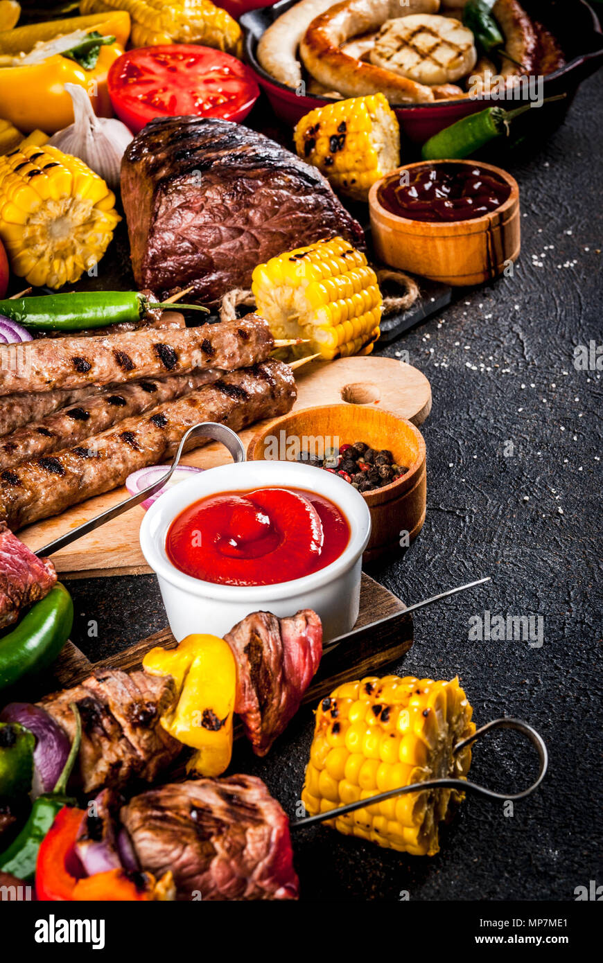 Sortiment verschiedene Barbecue Grill Fleisch, bbq Party fest - Shish Kebab, Würstchen, gegrillten Fleisch Filet, frisches Gemüse, Soßen, Gewürze, dunklen Rusty Stockfoto