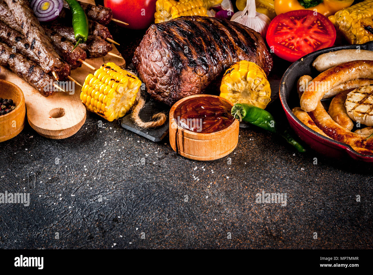 Sortiment verschiedene Barbecue Grill Fleisch, bbq Party fest - Shish Kebab, Würstchen, gegrillten Fleisch Filet, frisches Gemüse, Soßen, Gewürze, dunklen Rusty Stockfoto
