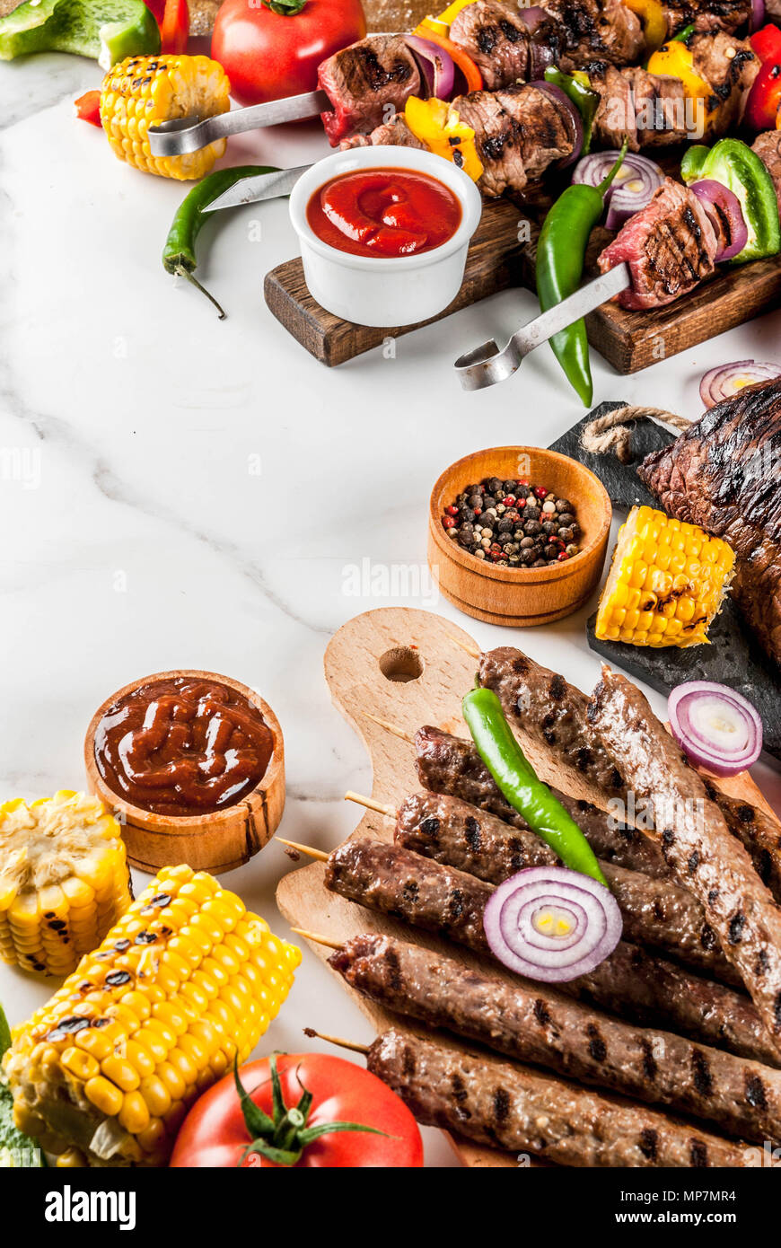 Sortiment verschiedene Barbecue Grill Fleisch, bbq Party fest - Shish Kebab, Würstchen, gegrillten Fleisch Filet, frisches Gemüse, Soßen, Gewürze, weiße Marb Stockfoto