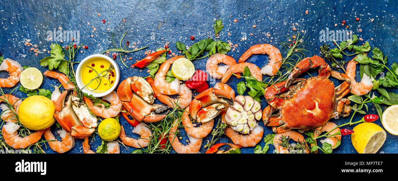 Baner. Frische rohe Meeresfrüchte - Garnelen und Krebse mit Kräutern und Gewürzen auf blauem Hintergrund. Kopieren Sie Platz. Stockfoto