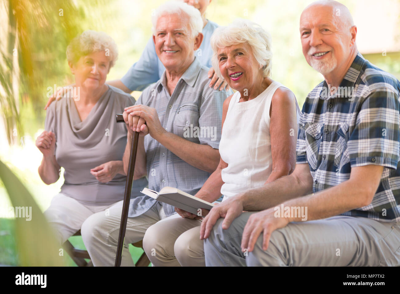 Lächelnde ältere Menschen verbringen die Zeit zusammen auf der Terrasse der Krankenpflege Haus Stockfoto