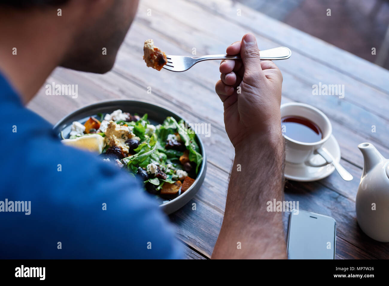 Mann an einem bistrotisch Essen leckeren Salat sitzen Stockfoto