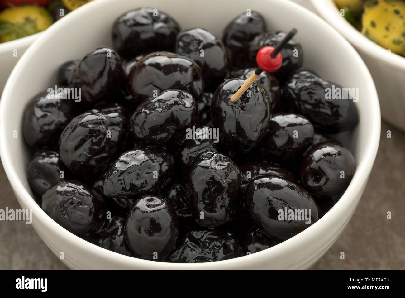 Schüssel mit glänzenden schwarzen Oliven als Snack Stockfoto