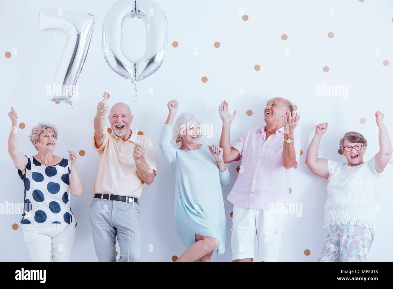 Positive Senioren Familie feiert Geburtstag des Großvaters mit silberfarbenen Ballons Stockfoto