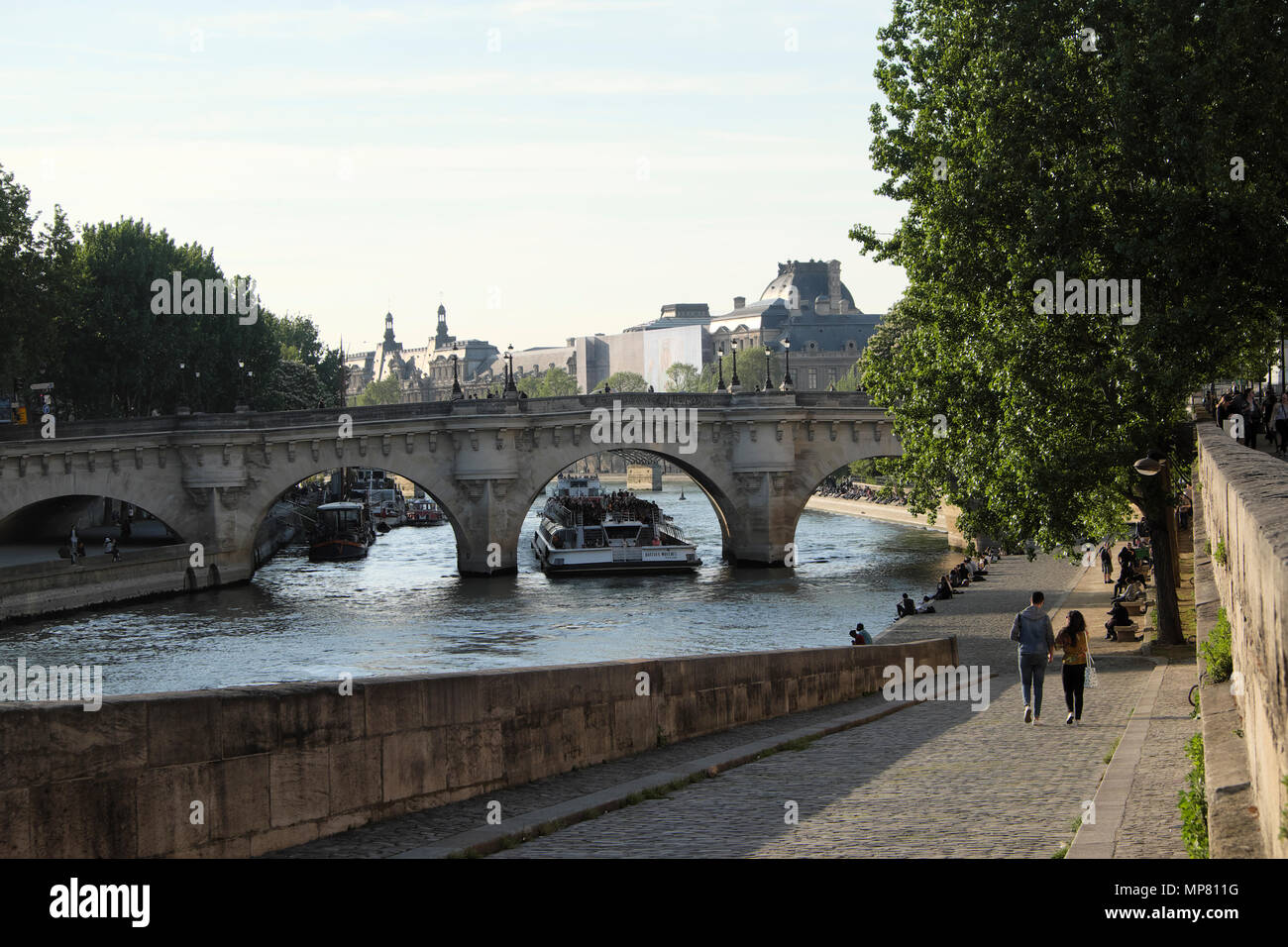 Touristenboot, das unter Pont Neuf vorbeifährt Blick auf die Brücke und Menschen, die am Kai entlang des linken Seineufers in Paris spazieren gehen, Frankreich KATHY DEWITT Stockfoto