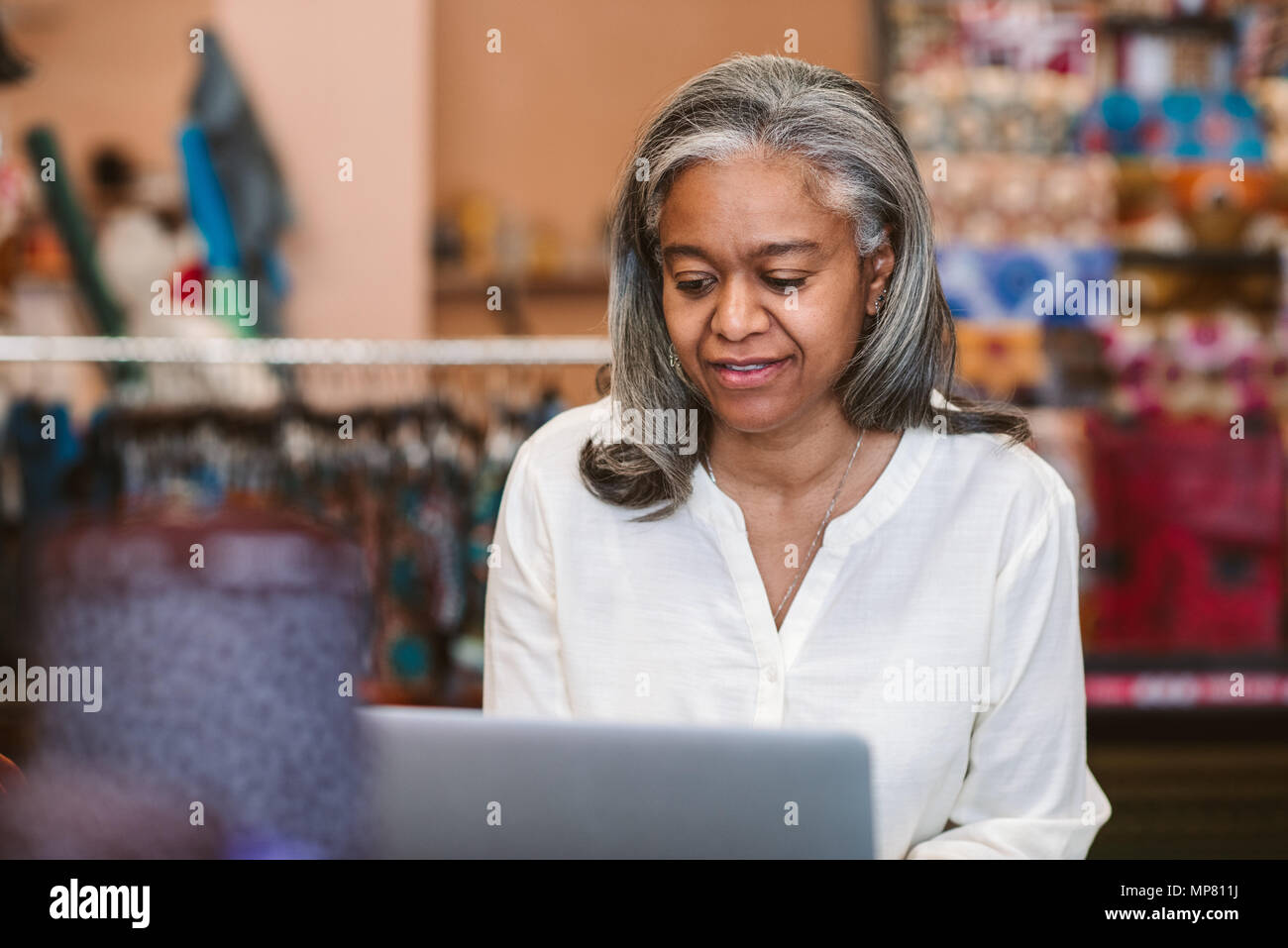 Reife Frau, die an einem Notebook arbeitet in ihrem Gewebe shop Stockfoto