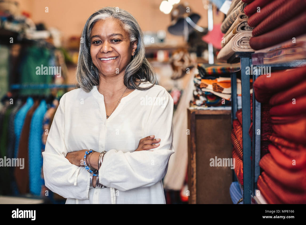 Lächelnd reife Frau, die in ihrem bunten Stoff shop Stockfoto