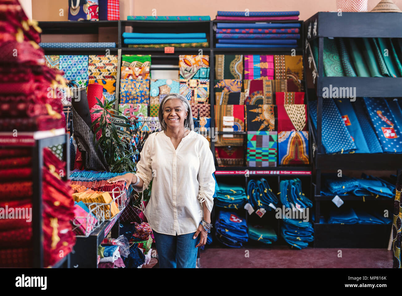 Reife Frau lächelnd, während in ihren Textilien Shop arbeiten Stockfoto