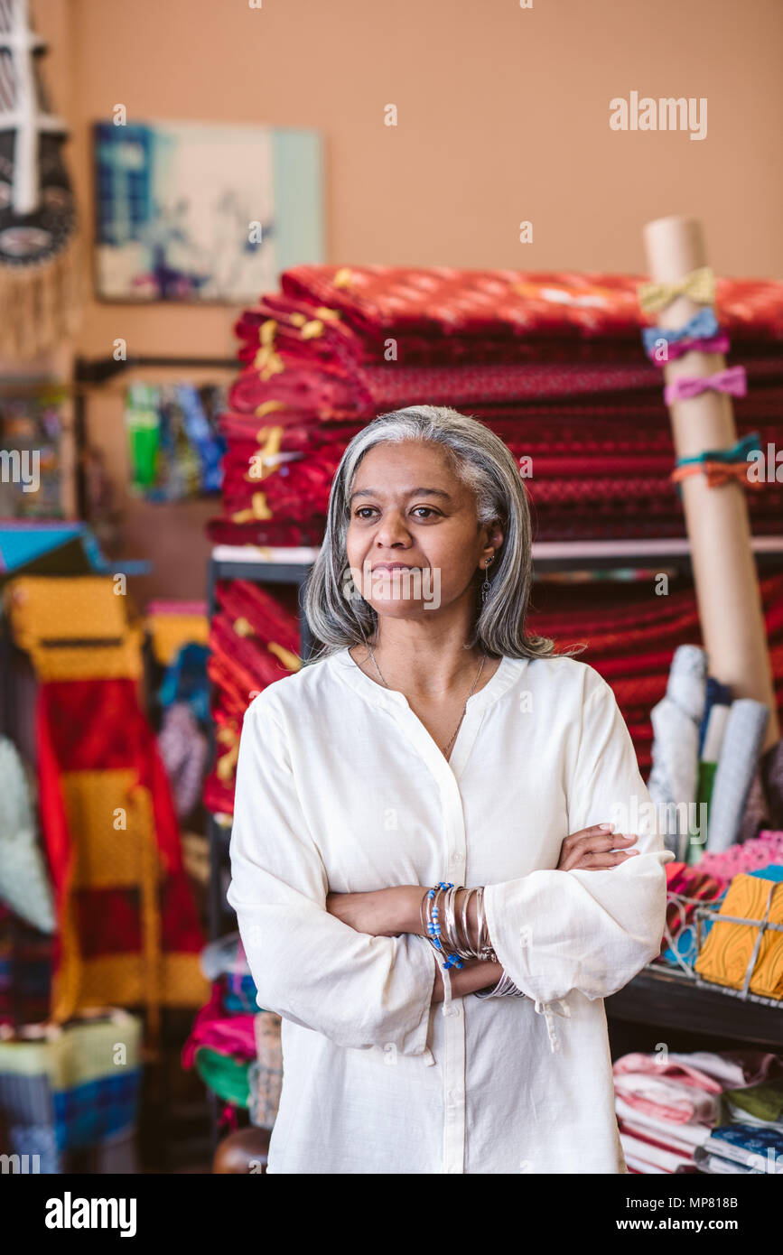 Reifen Stoff shop besitzer stehen unter ihrem farbenfrohen Textilien Stockfoto