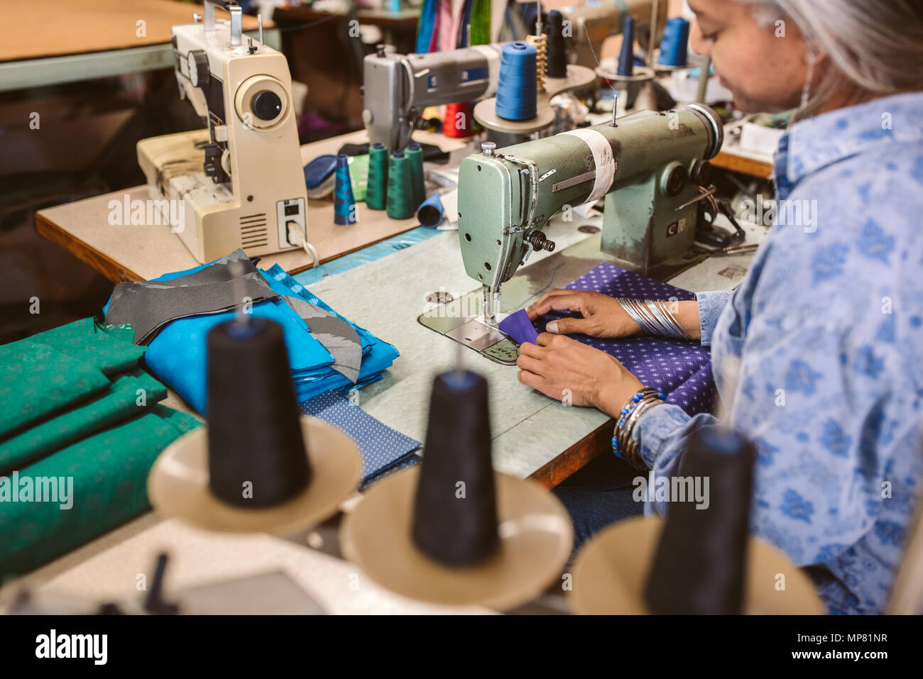 Reife Frau an einer Nähmaschine in ihrer Werkstatt Stockfoto