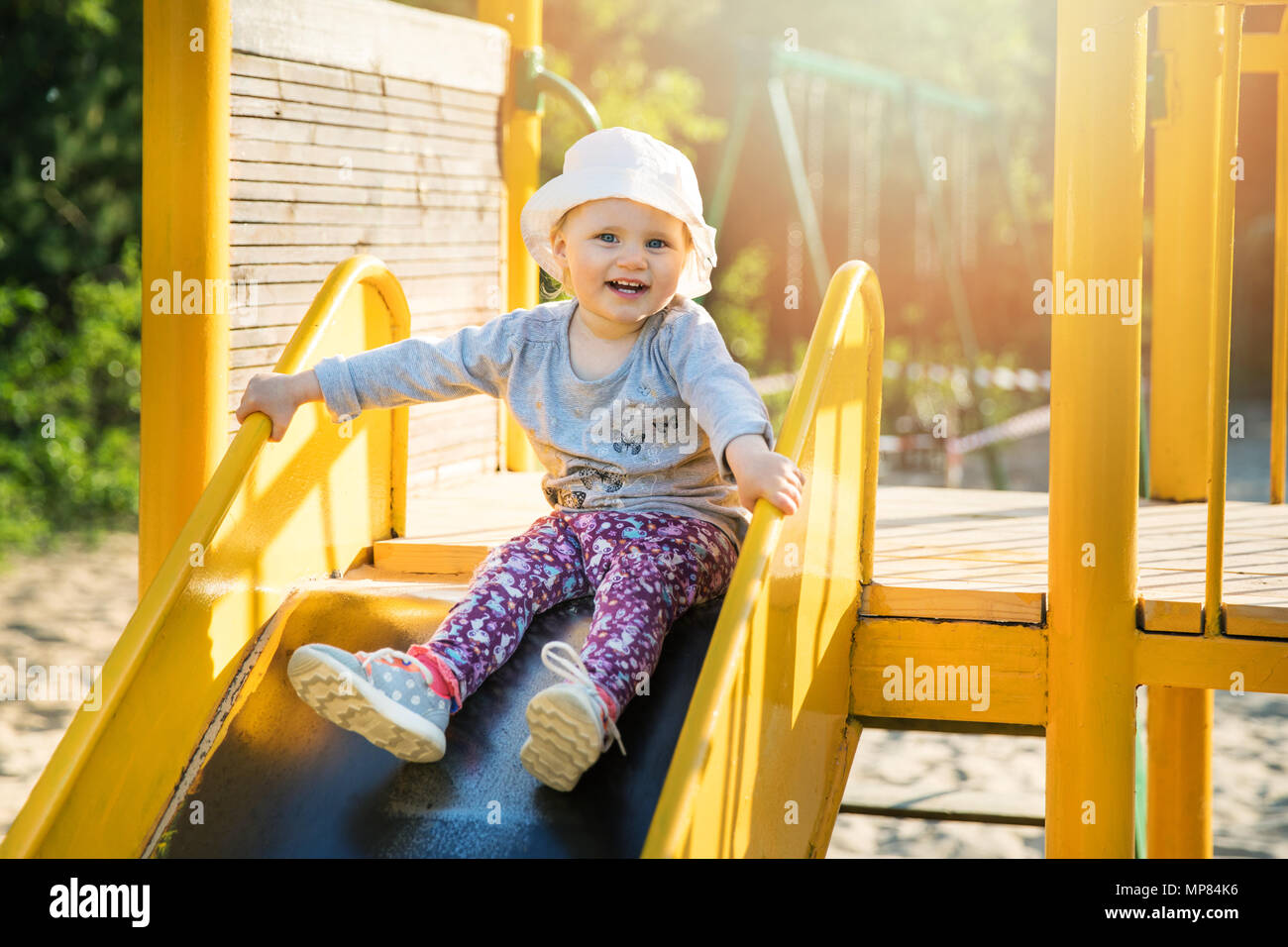 Glücklich lächelnde Kind auf Schieberegler am Spielplatz im Freien Stockfoto