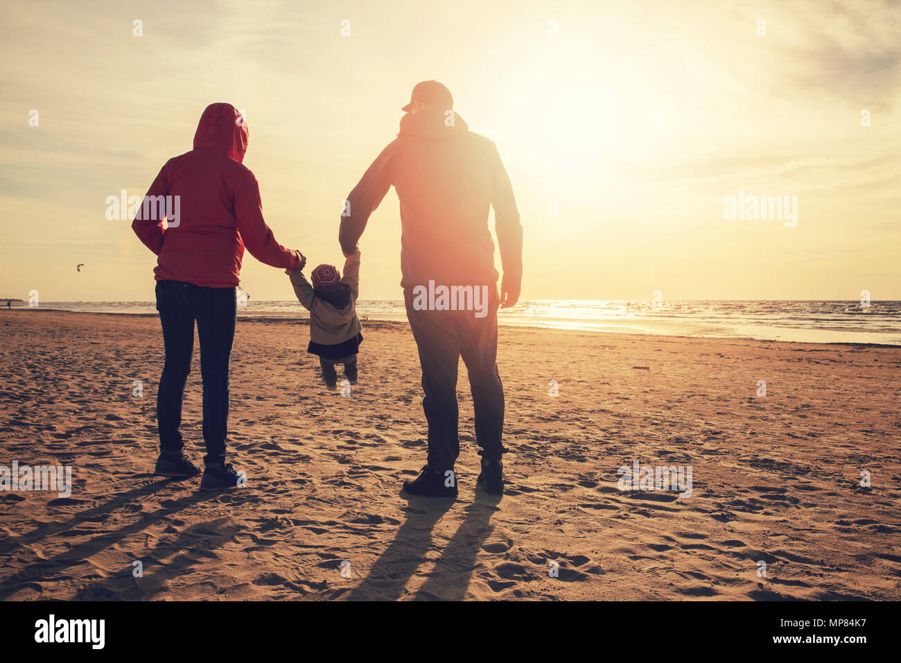 Mutter und Vater Kind durch schwingen die Arme am Strand bei Sonnenuntergang Stockfoto
