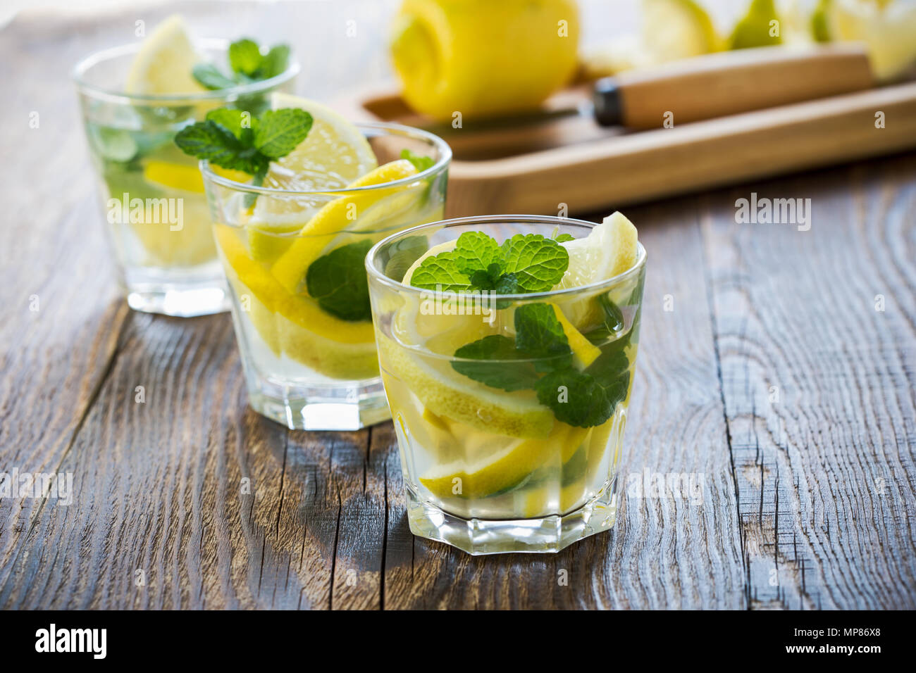 Frische hausgemachte Limonade mit Zitronenscheiben und frischer Minze auf hölzernen Tisch Stockfoto