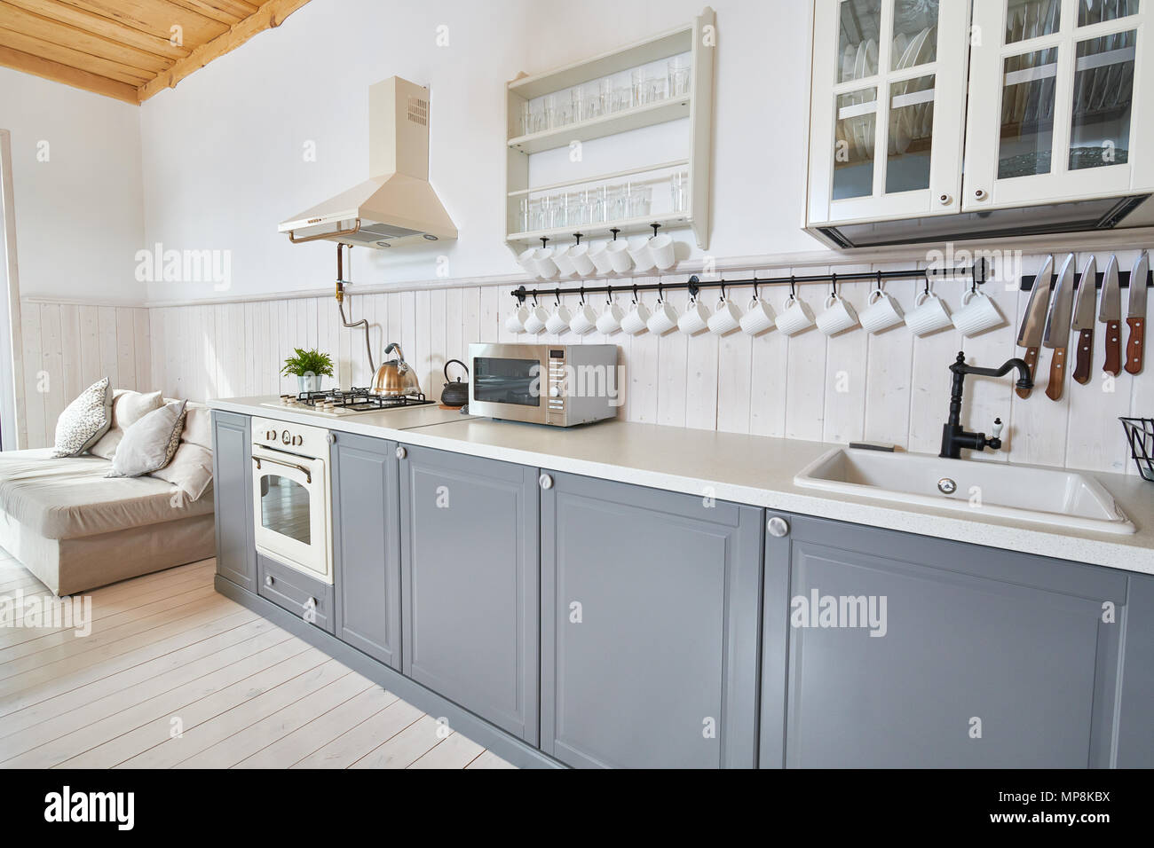 Wide Angle Shot der modernen offenen Wohnzimmer mit grauen Küche Zähler und weißen Möbeln im minimalistischen skandinavischen Design, Kopie Raum Stockfoto